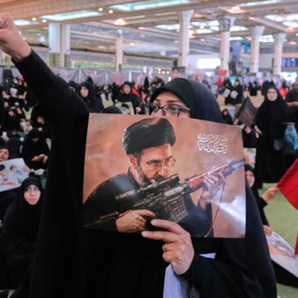 Una doliente corea consignas mientras sostiene un cartel con una imagen del líder supremo de Irán, el ayatolá Mojtaba Jamenei.