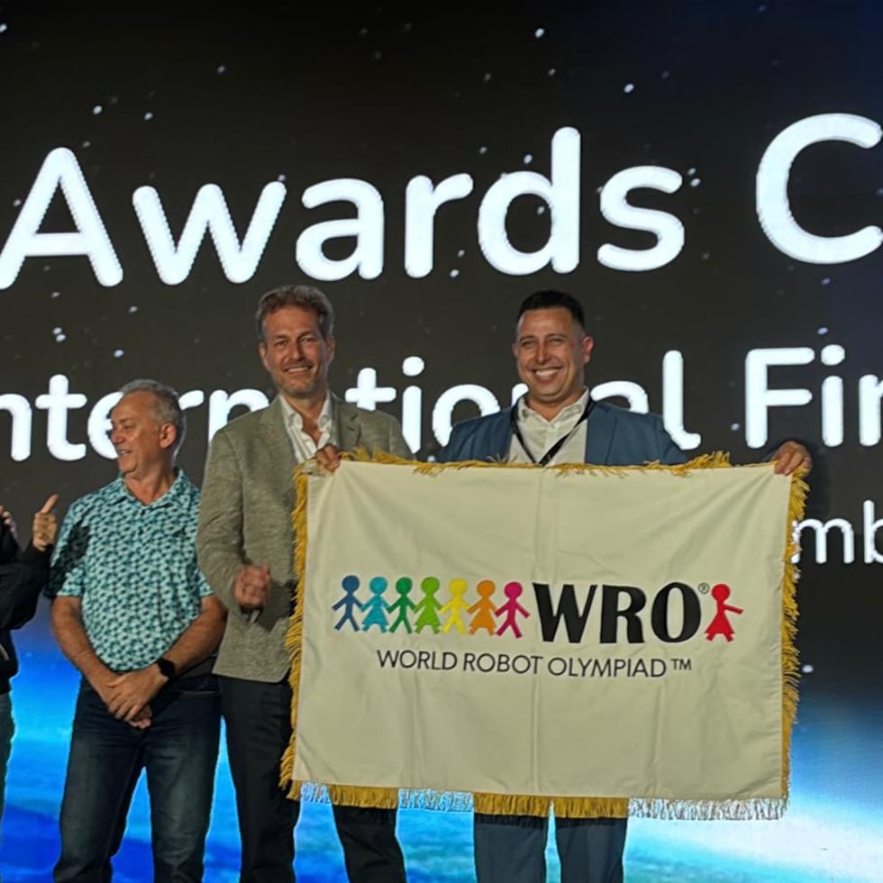 En primer plano, Claus Ditlev Christensen (izquierda), secretario general de la WRO Association, y César Cabrera, principal oficial ejecutivo de Techno Inventors, celebran que Puerto Rico fue escogido como sede de la Final Internacional de la Olimpiada Mundial de Robótica 2026.