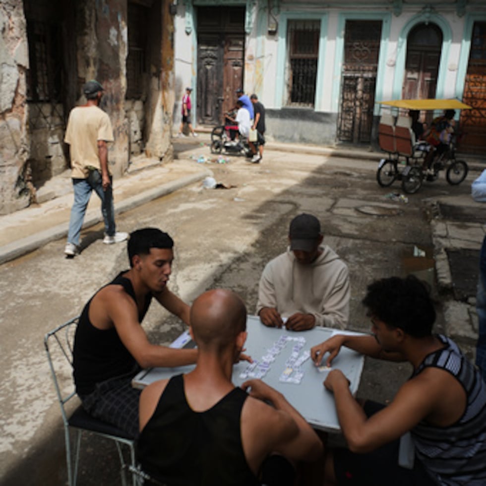 Varias personas juegan al dominó en el exterior durante un apagón en La Habana, el martes 17 de marzo de 2026. (AP Photo/Ramon Espinosa)