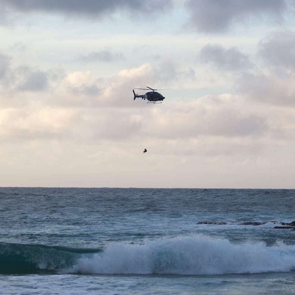 En la foto, personal de FURA e la policía usó su helicóptero para rescatar a dos buzos que fueron arrastrados por el mar mientras intentaban recuperar el cuerpo de un bañista. en Manatí.