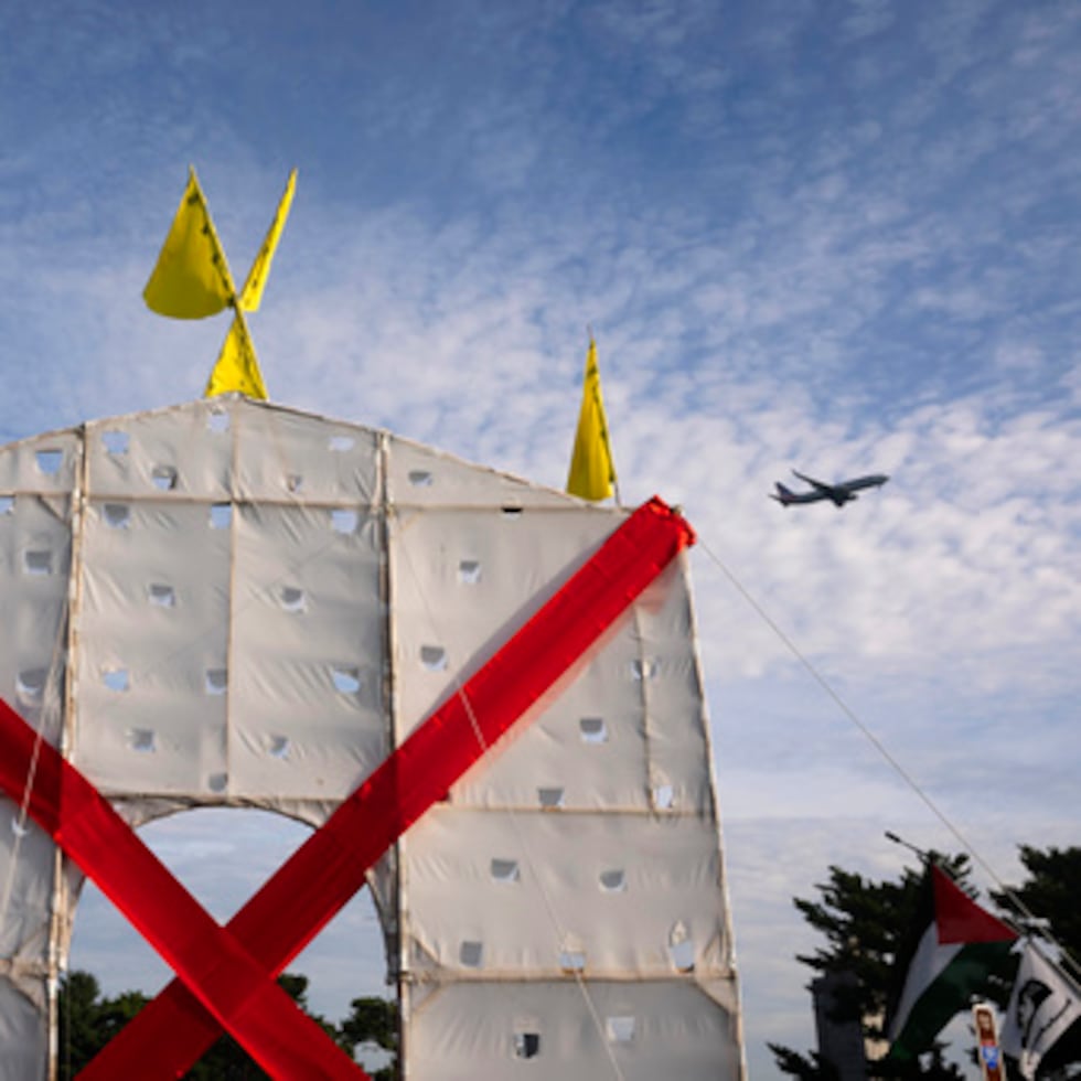 Un avión sobrevuela una estructura en forma de arco invertido que han levantado los manifestantes en el Memorial Circle para protestar contra el proyecto del Arco del Triunfo.