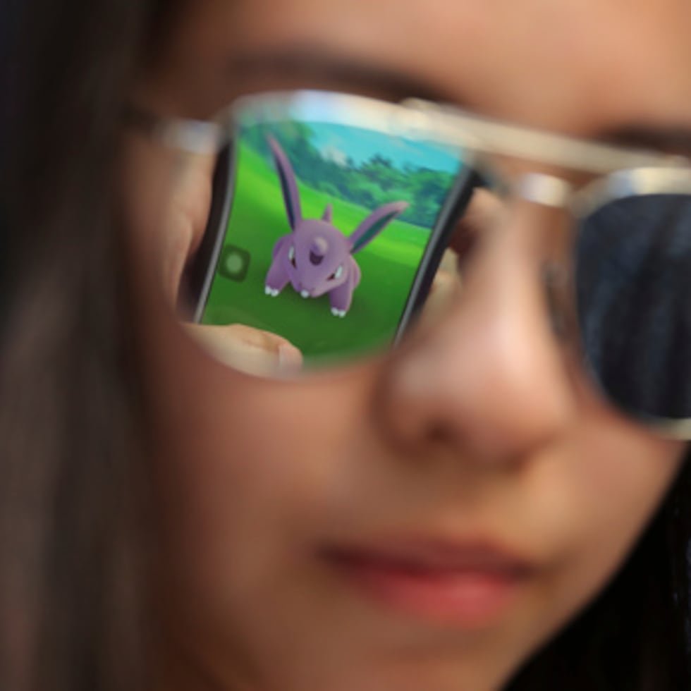 Una pantalla de móvil se refleja en las gafas de sol de una aficionada mientras juega a "Pokemon Go" en Hong Kong.