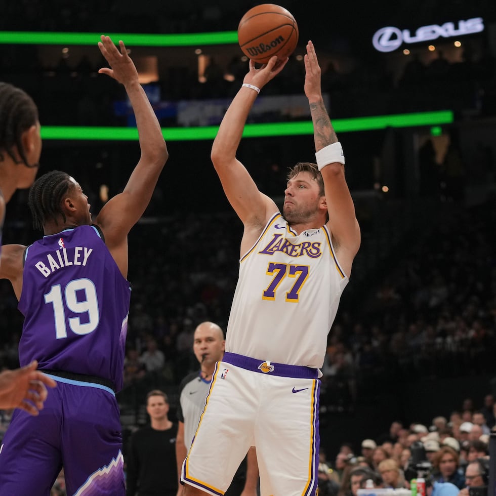 El delantero y guardia de los Lakers de Los Ángeles, Luka Dončić (77), busca hacer un tiro mientras lo defiende el delantero del Jazz de Utah, Ace Bailey (19), durante la primera mitad de un partido de básquetbol de la NBA, el domingo 25 de octubre de 2026, en Salt Lake City. (Foto AP/Bethany Baker)