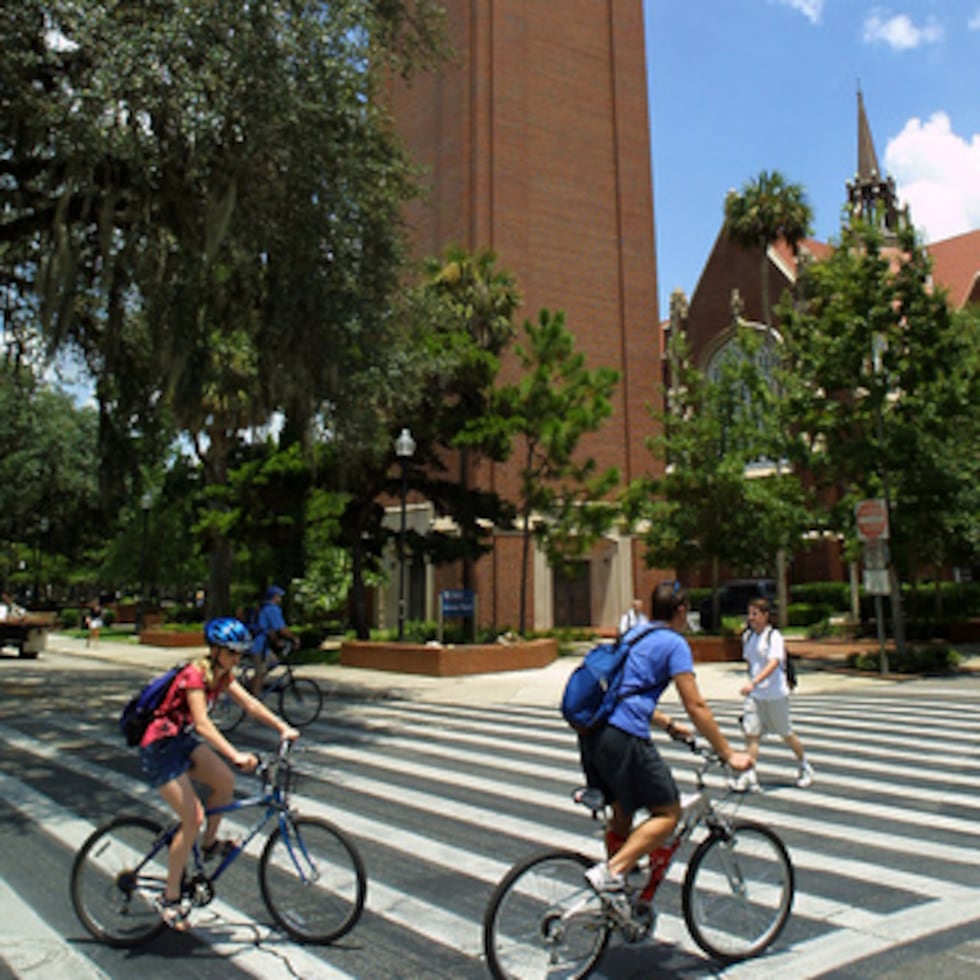 Estudiantes de la Universidad de Florida pasan por un paso de peatones cerca de la emblemática Century Tower en Gainesville, Florida.