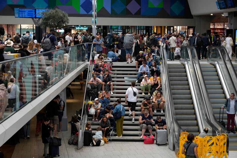Pasajeros esperan sentados en las escaleras en la estación Gare de Montparnasse, después de que fuegos intencionales paralizaran varias vías del trenes a horas de comenzar los Juegos Olímpicos de 2024 en París.