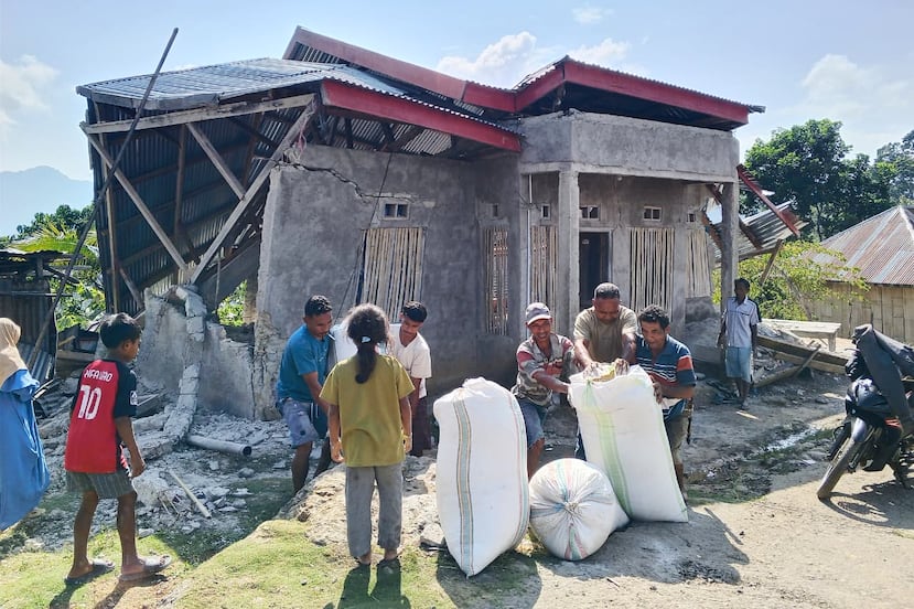 Varias personas retiran sacos de grano de una casa destruida por un terremoto en Manggarai Oriental.