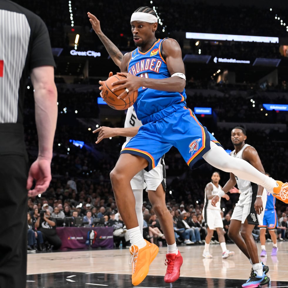 Shai Gilgeous-Alexander atrapa un rebote por el Thunder de Oklahoma City en el primer partido de la temporada, ante los Spurs de San Antonio.