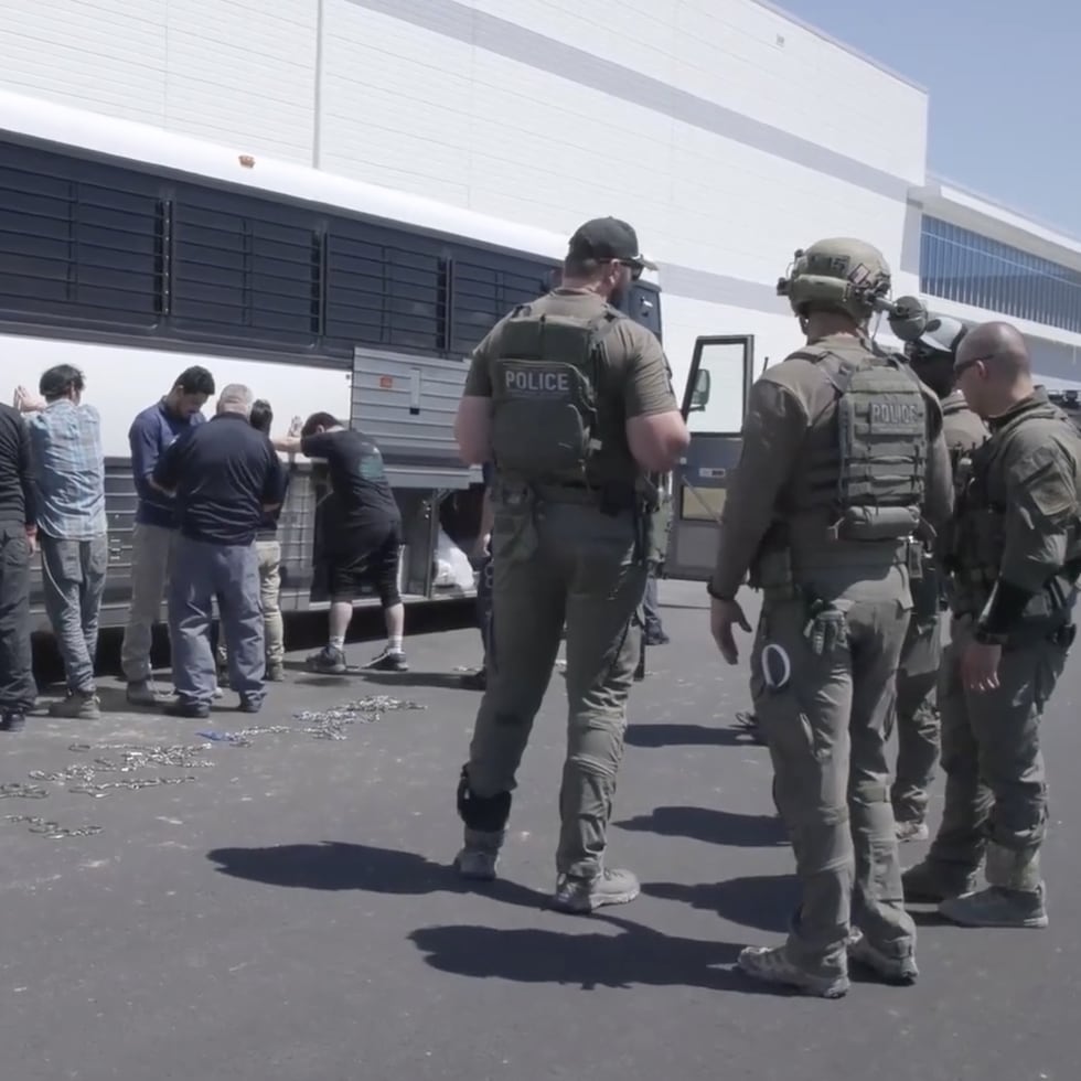 En esta imagen tomada de un video difundido por el Servicio de Inmigración y Control de Aduanas de Estados Unidos muestra a empleados de una planta mientras esperan a que se les coloquen grilletes en la planta automotriz de Hyundai Motor Group, el 4 de septiembre de 2025, en Ellabell, Georgia