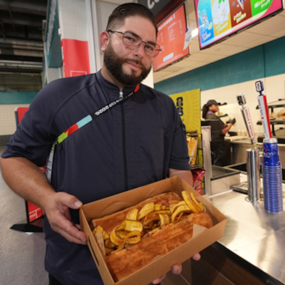 Lázaro Luya, el chef encargado del puesto de comida de Sol Cubano, muestra su plato especial —una sartén con lechón y mariquitas frescas— en el Miami Stadium.