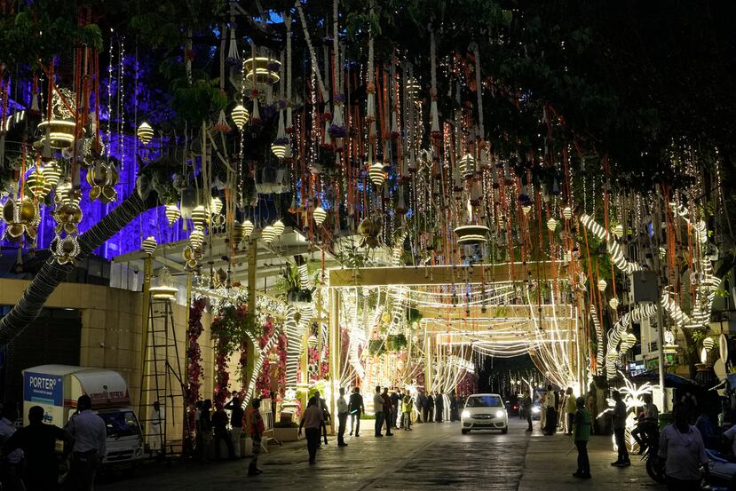 People walk past the Antilia mansion, house of billionaire Mukesh Ambani, while it is lit up ahead of his son Anant Ambani and Radhika Merchant's wedding in Mumbai, India, Wednesday, July 10, 2024. (AP Photo/Rajanish Kakade)