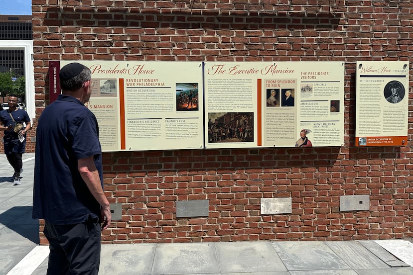 Visitantes observan los paneles educativos reinstalados sobre la esclavitud en el sitio donde se encontraba la casa del presidente George Washington en Filadelfia, el miércoles 15 de julio de 2026. (Foto AP/Tassanee Vejpongsa)