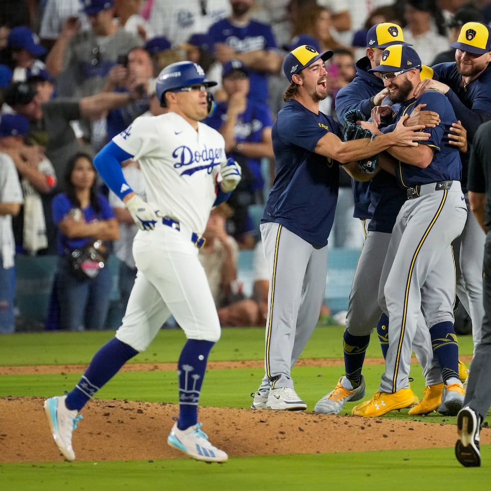El boricua Kike Hernández (izquierda) abandonando el terreno de juego, mientras los Brewers de Milwaukee celebran su victoria sobre los Dodgers de Los Ángeles y su pase a la Serie Mundial.