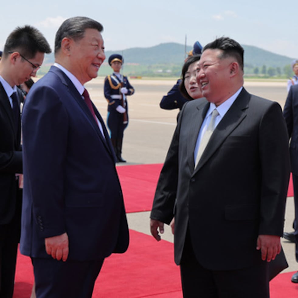 En esta foto facilitada por el gobierno norcoreano, el líder norcoreano Kim Jong Un, delante a la derecha, saluda al presidente chino Xi Jinping, en el centro a la izquierda, a la llegada de este último al aeropuerto de Pyongyang, el lunes 8 de junio de 2026.