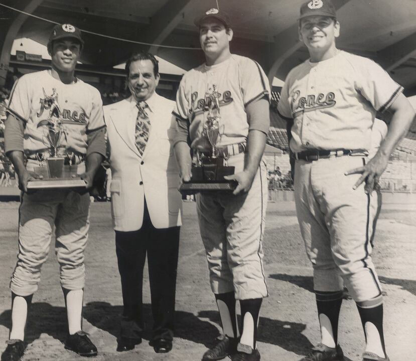 Santos Alomar (izq.) recibe un galardón, al tiempo que también posa con los jugadores Quique Rivera y Wito Conde.