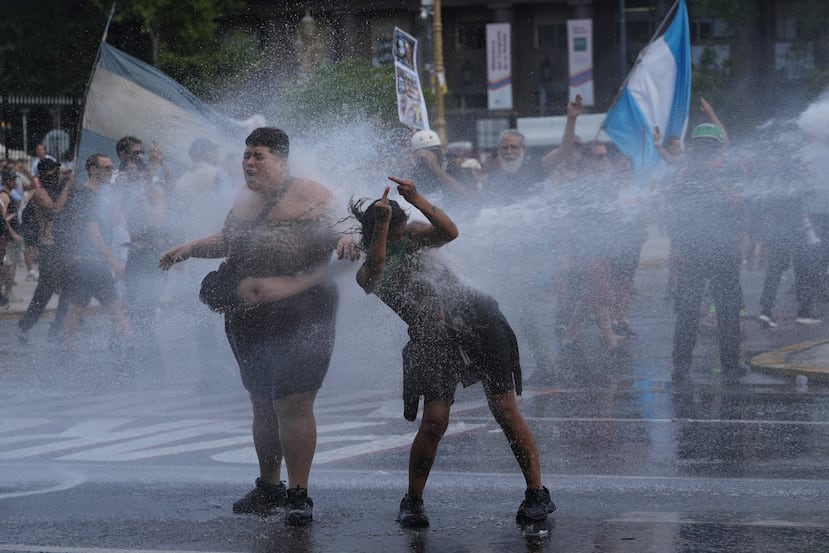 EDS NOTE: OBSCENITY - Protesters are sprayed by a police water cannon during a march by trade unions and opposition groups against a labor reform bill proposed by President Javier Milei's government in Buenos Aires, Argentina, Thursday, Feb. 19, 2026.(AP Photo/Rodrigo Abd)