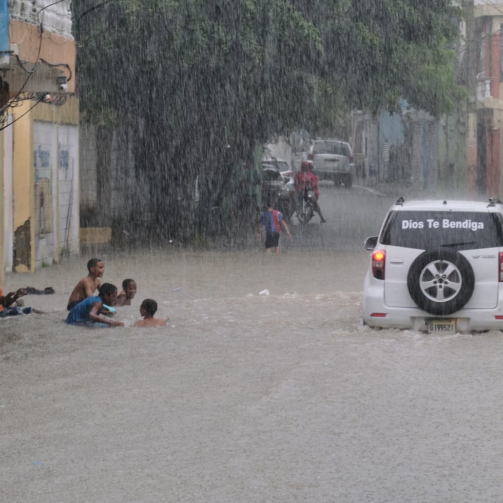 Un grupo de niños juega en una calle inundada por las lluvias que descargó el huracán Melissa al pasar cerca de República Dominicana.