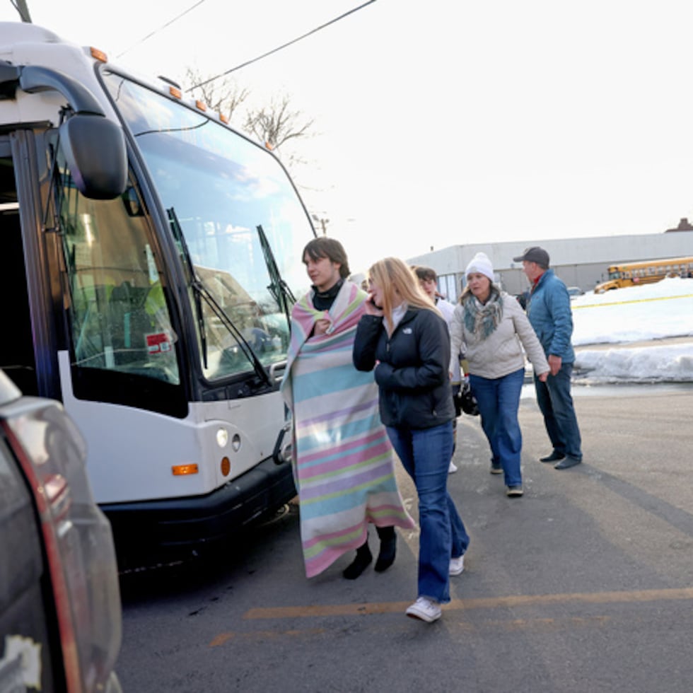 Estudiantes de hockey de secundaria suben a un autobús de transporte público cerca del Lynch Arena en Pawtucket, Rhode Island, después de un tiroteo en la pista de hielo, el lunes 16 de febrero de 2026. (AP Photo/Mark Stockwell)