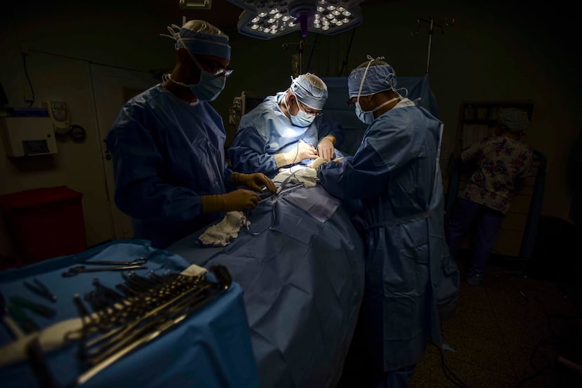 El doctor Reynold López, uno de los pocos cirujanos oncólogos que quedan en Puerto Rico, realiza una operación de tiroides junto a médicos residentes en el hospital Dr. Isaac González Martínez. (AP)