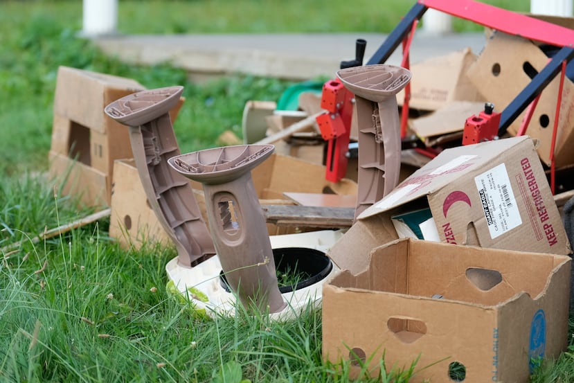 Baby furniture is seen among debris on the front lawn of home where authorities say they removed 16 children and arrested four adults in Hamden, Ohio, Wednesday, July 1, 2026. (AP Photo/Carolyn Kaster)