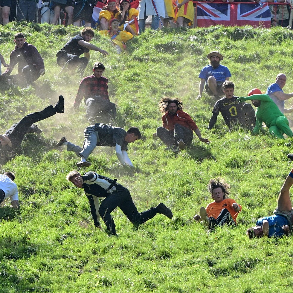 Los participantes compiten el lunes en la categoría de descenso masculino del tradicional concurso anual de rodar quesos en Cooper's Hill en Brockworth, Gloucestershire, Inglaterra.