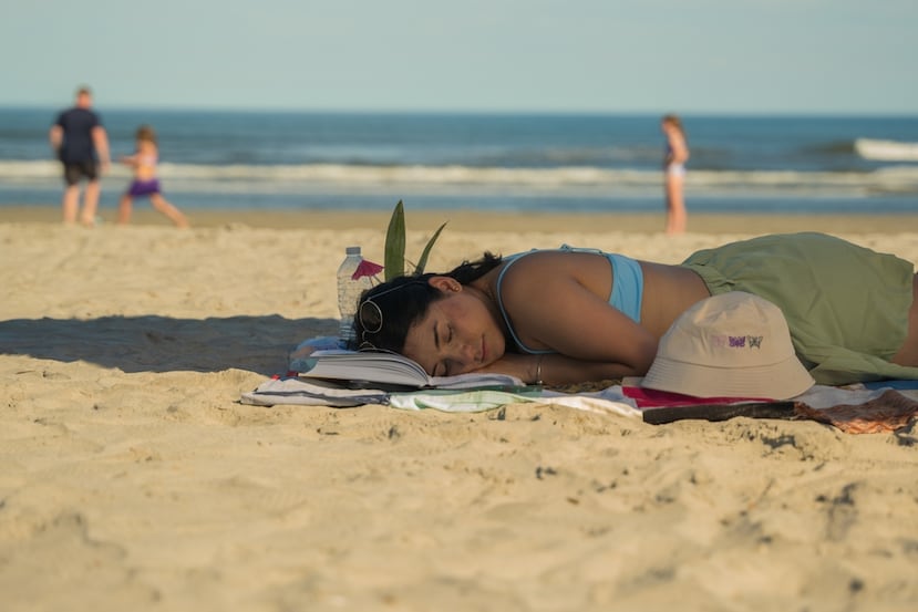 Un bañista se echa una siesta en la playa.