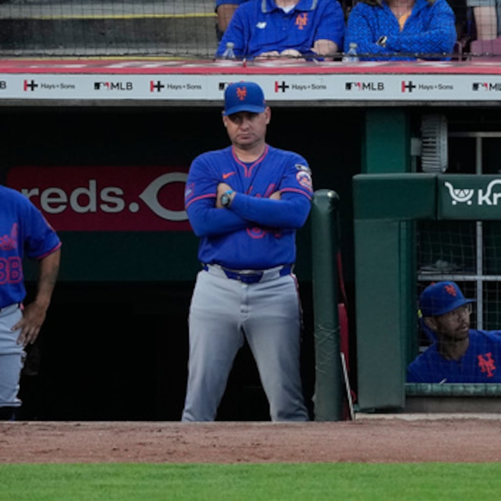 El entrenador de los Mets de Nueva York, Carlos Mendoza (en el centro), observa desde el banquillo durante la cuarta entrada de un partido de béisbol contra los Reds de Cincinnati.