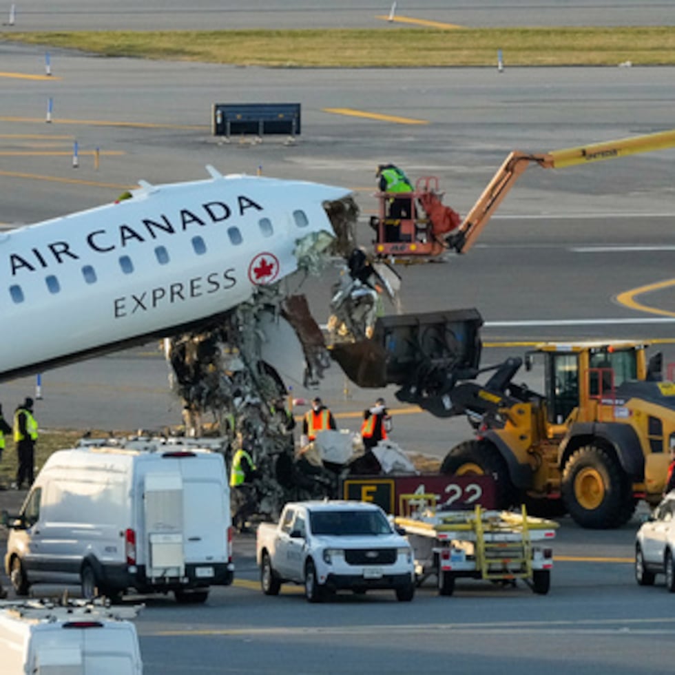 Trabajadores de mantenimiento de aeronaves cortaron el martes los escombros que cuelgan de los restos de un avión de Air Canada Express.