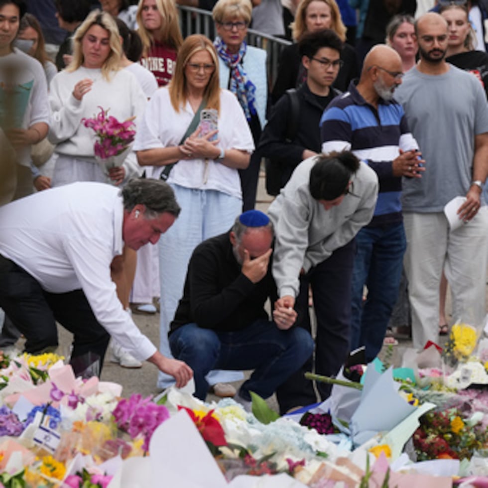 La gente llora y ofrece flores en un monumento floral por las víctimas del tiroteo del domingo en el Bondi Pavilion de Bondi Beach.