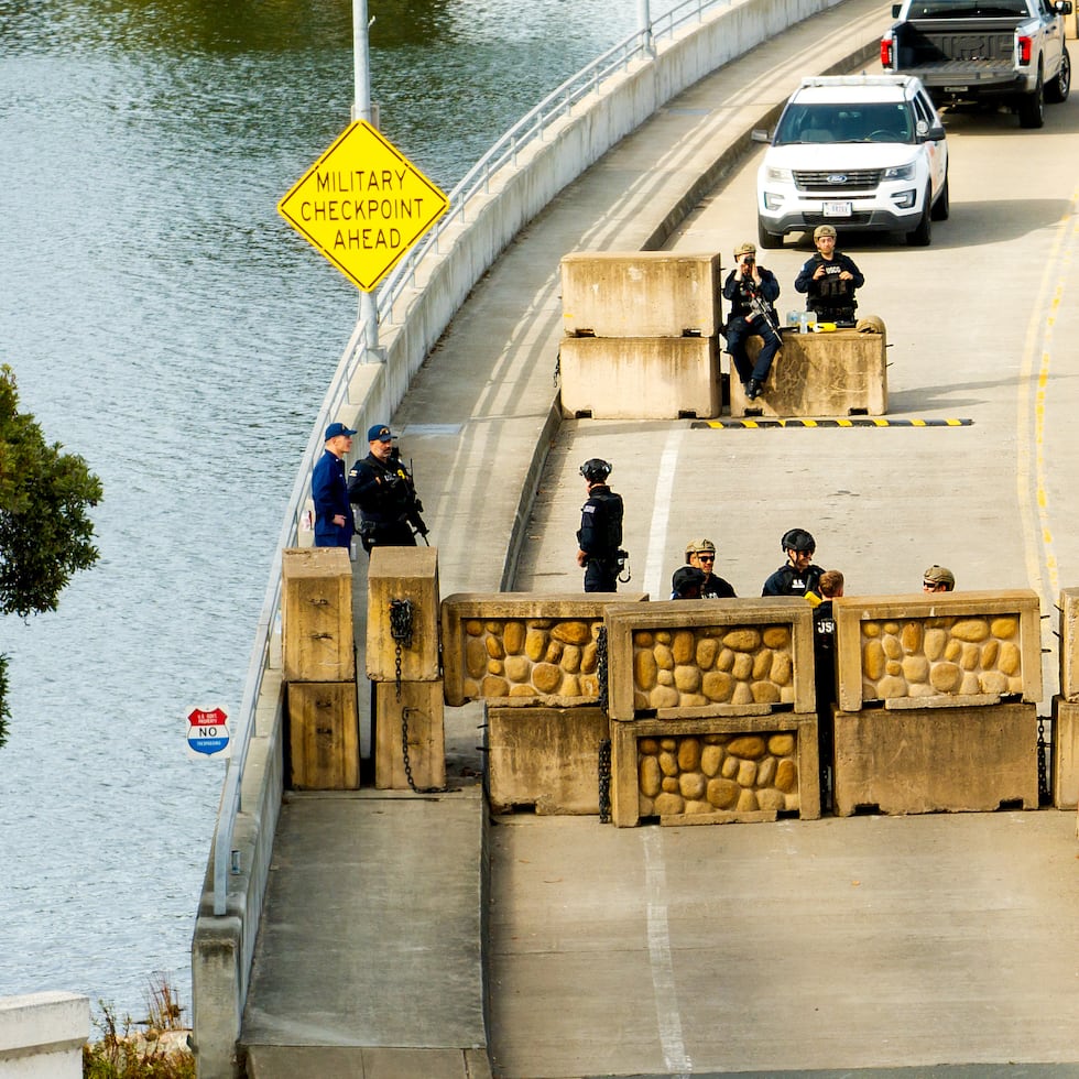 Elementos de la Guardia Costera vigilan tras una barrera en la Base Alameda  el viernes 24 de octubre de 2025, en Oakland, California. La barrera se erigió ese mismo día después de que agentes policiales dispararan contra un vehículo que retrocedía hacia ellos.