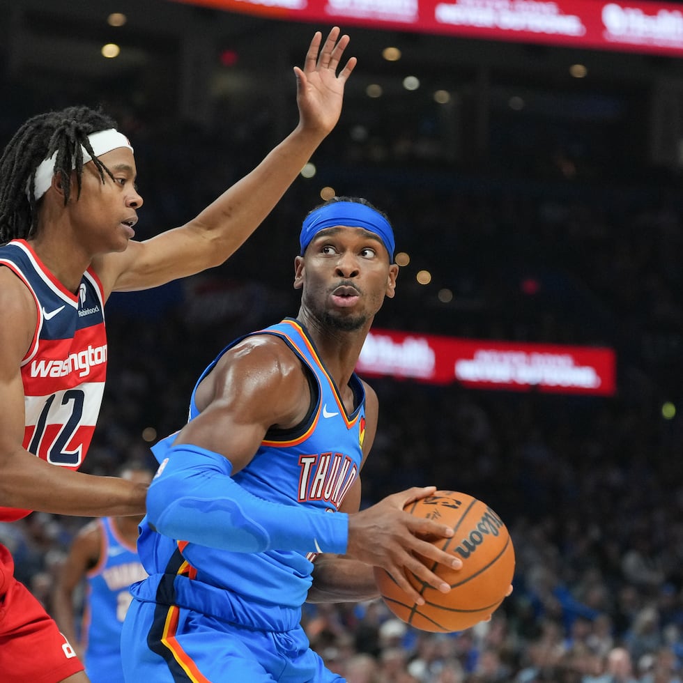 Shai Gilgeous-Alexander, derecha, del Thunder de Oklahoma City, busca a un compañero desmarcado para pasar el balón ante la presión defensiva de Tre Johnson, izquierda, de los Wizards de Washington, durante la segunda mitad del juego de baloncesto de la NBA, el jueves 30 de octubre de 2025, en Oklahoma City. (AP Foto/Kyle Phillips)