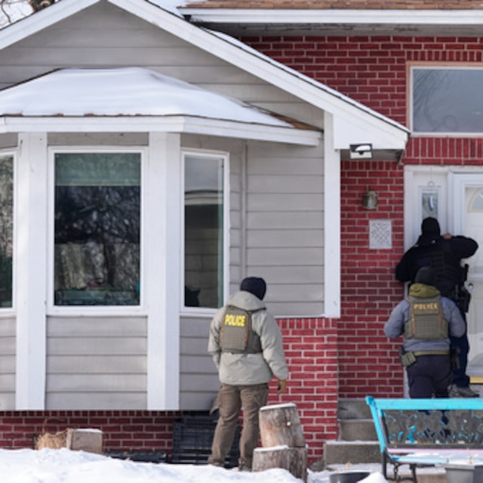 Agentes federales de inmigración miran por la ventana de una vivienda, el martes 20 de enero, en Maplewood, Minnesota.