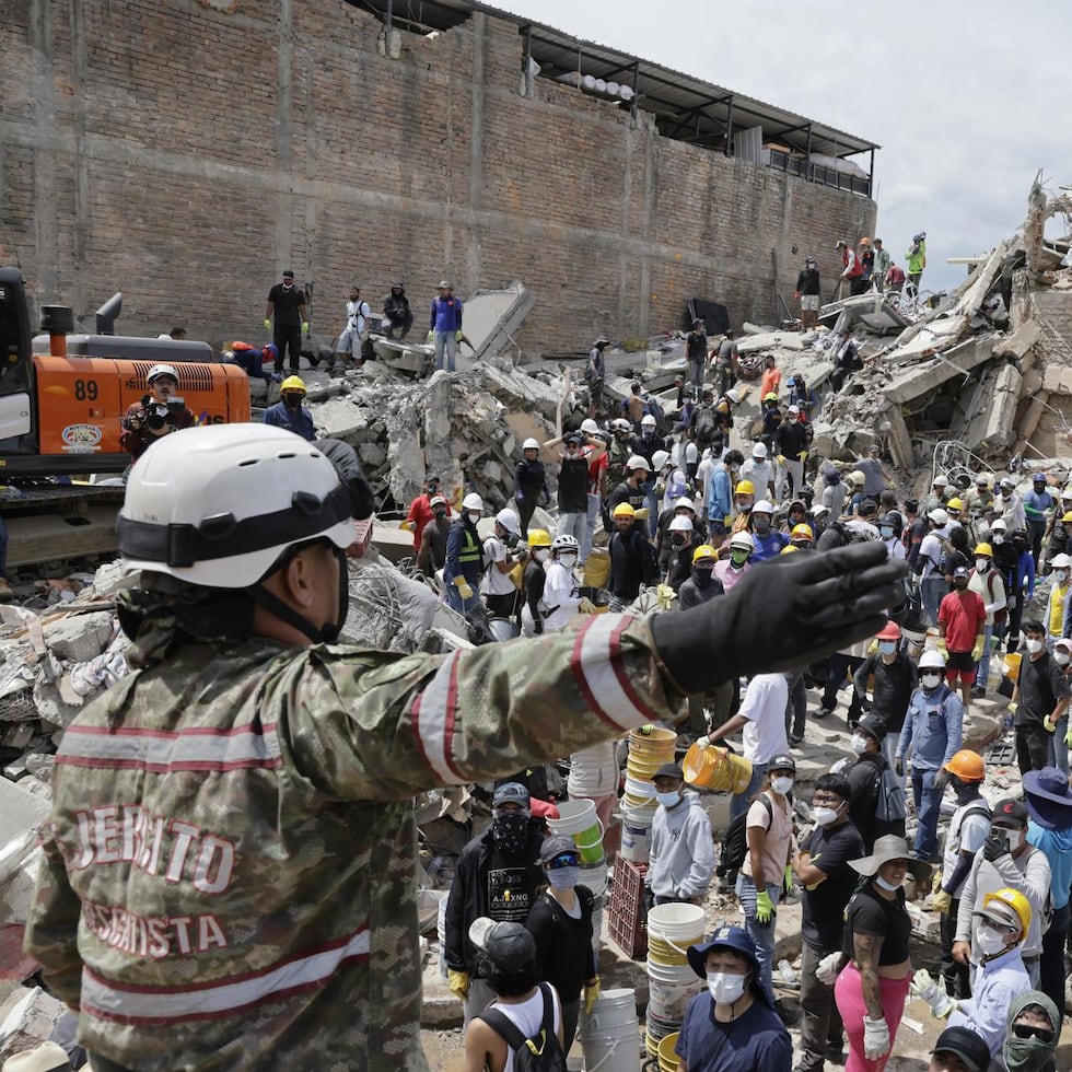 Una rescatista del Ejercito de Colombia da indicaciones a un grupo de voluntarios que realiza labores de búsqueda en edificaciones destruidas por el terremoto de magnitud 7.4 del pasado lunes, este miércoles en Pereira (Colombia).