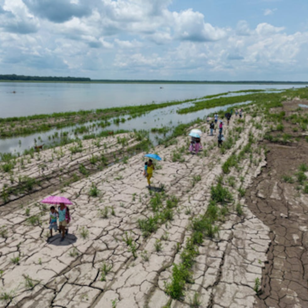 Unas personas caminan por un tramo del río Amazonas que muestra signos de sequía en Santa Sofía, a las afueras de Leticia, en Colombia.