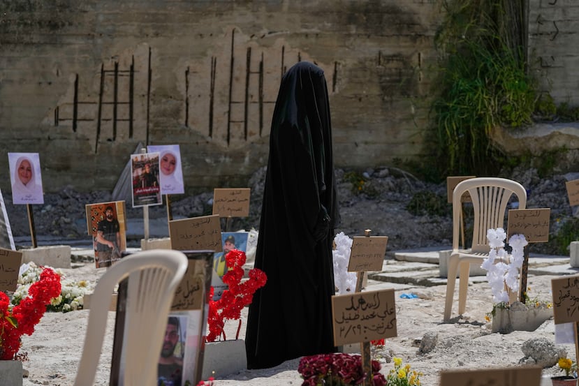 Una mujer con velo camina por una fosa común donde civiles y combatientes de Hezbolá muertos por ataques aéreos israelíes están enterrados temporalmente en la ciudad portuaria de Sidón, Líbano, el martes 14 de abril de 2026. (Foto AP/Mohammed Zaatari)