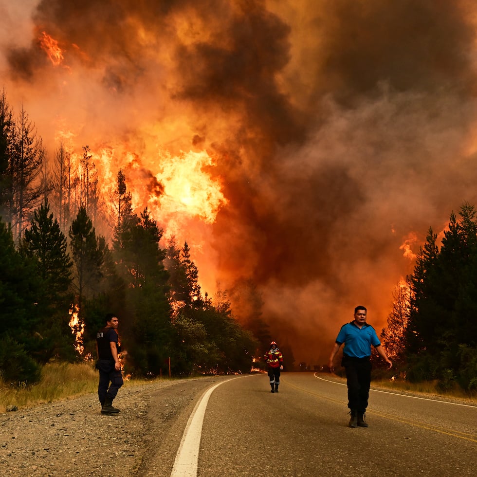 Personas caminan por una carretera mientras un incendio forestal arde en El Hoyo, Patagonia, Argentina.