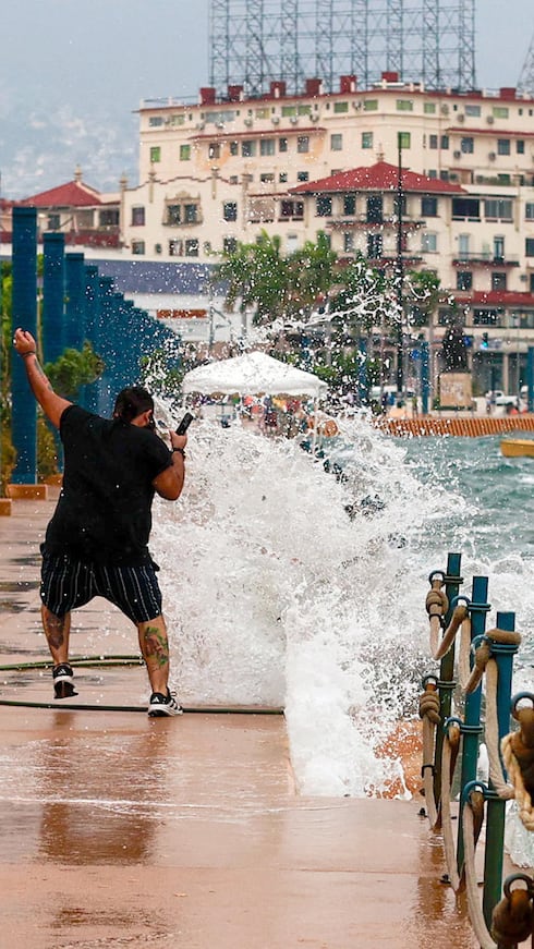 Una persona reacciona ante el fuerte oleaje provocado por el paso del huracán Polo, este miércoles, en Acapulco, Guerrero, México. El fenómeno, debilitado a categoría 4, mantiene un desplazamiento lento frente a las costas del Pacífico mexicano.