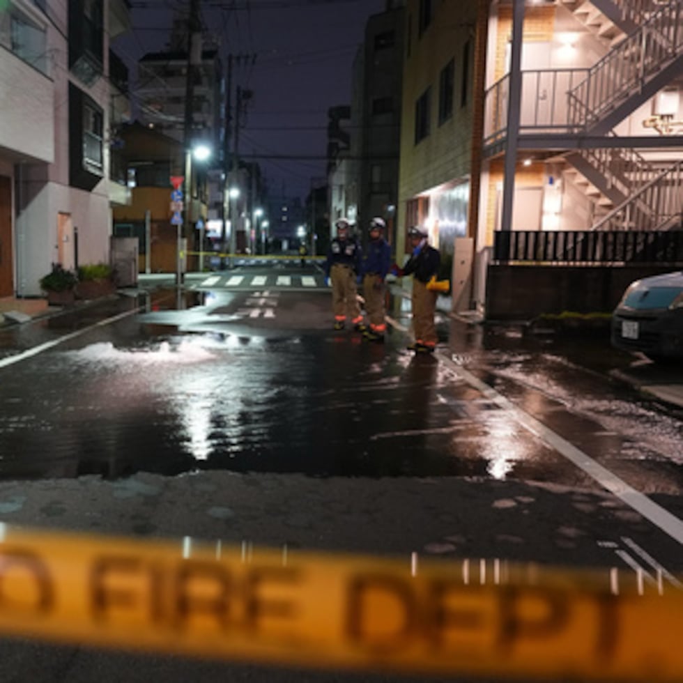Los equipos de primera intervención del Cuerpo de Bomberos de Tokio se encuentran en una calle parcialmente inundada, tras la rotura de una tubería de agua a raíz de un terremoto que sacudió la zona el domingo.