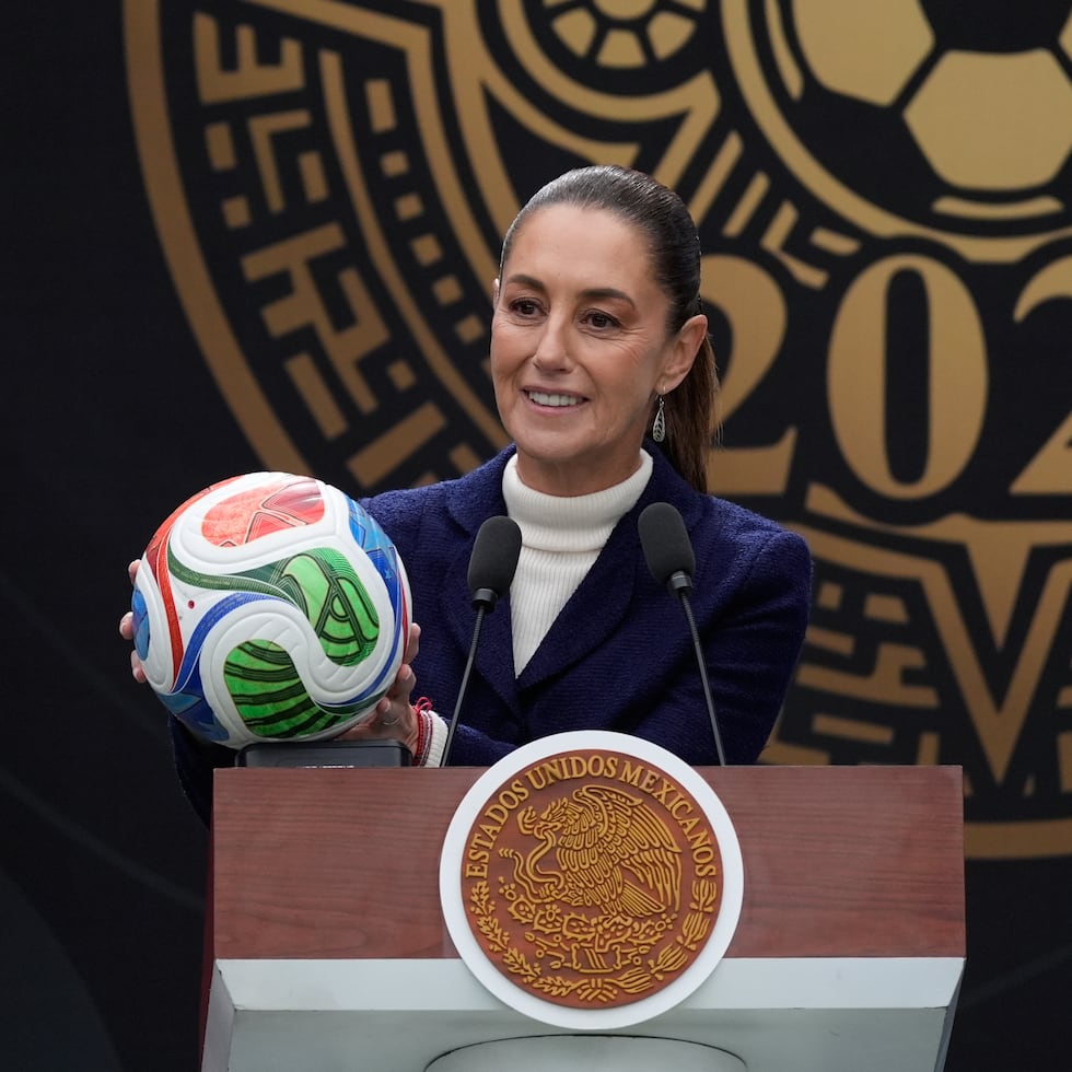 La presidenta mexicana Claudia Sheinbaum sostiene un balón de fútbol durante una rueda de prensa en la que habló sobre los preparativos de cara a la Copa Mundial.