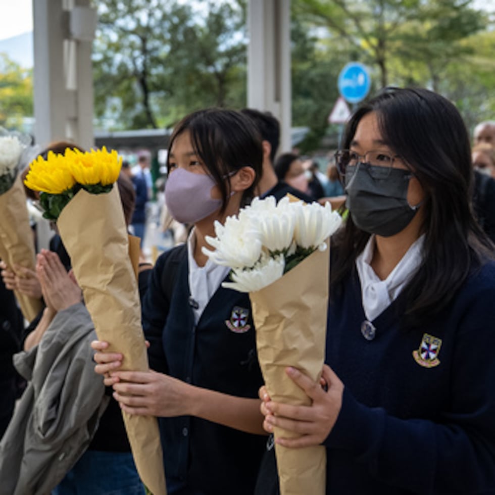 Un grupo de personas ofrece flores a las víctimas cerca del lugar donde el miércoles se produjo un mortífero incendio en Wang Fuk Court, una urbanización del distrito de Tai Po, en los Nuevos Territorios de Hong Kong, el lunes 1 de diciembre de 2025. (AP Photo/Chan Long Hei)