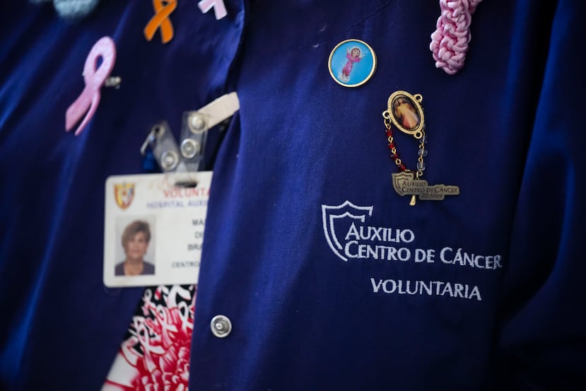 Mariam luce uniformada con un abrigo caracterizado por unos alfileres de diversos lazos y símbolos cristianos que lleva como aplicaciones sobre la tela, que le han sido obsequiado los pacientes a lo largo de su voluntariado de unos 9 años.