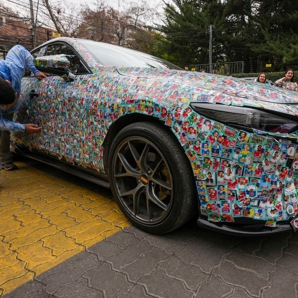 El auto del influencer chileno Ariel Osses se detiene en el estacionamiento de un hogar para niños con cáncer para que los pequeños puedan pegar más calcomanías de álbumes de fútbol del Mundial, que él les proporciona.