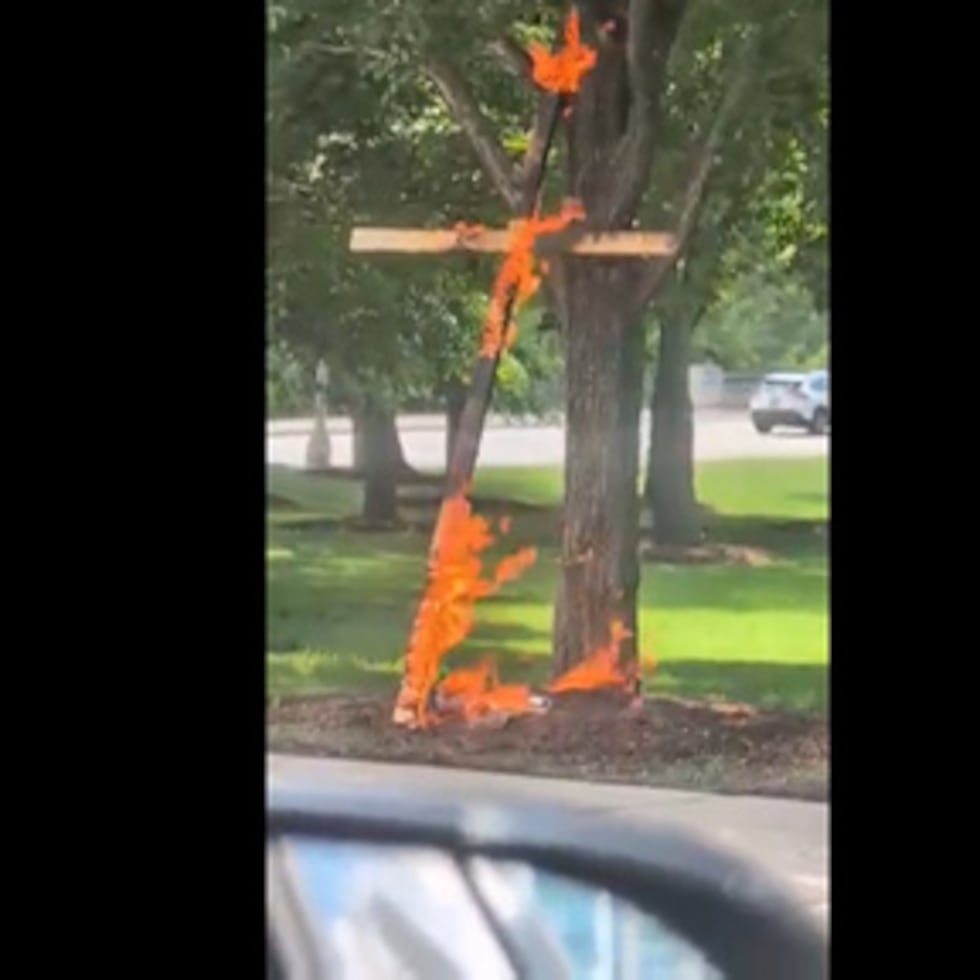 Esta imagen extraída de un vídeo grabado por la conductora Keinika Carlton muestra una cruz de madera envuelta en llamas de color naranja brillante, apoyada contra un árbol en el Grant Park de Chicago, el martes 9 de julio de 2026.