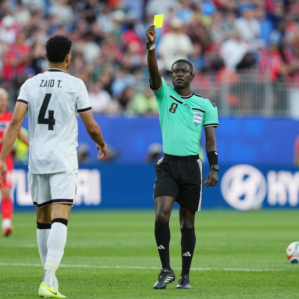El árbitro Pierre Ghislain Atcho muestra una tarjeta amarilla al iraquí Zaid Tahseen durante el partido del Grupo I de la Copa del Mundo entre Irak y Noruega.
