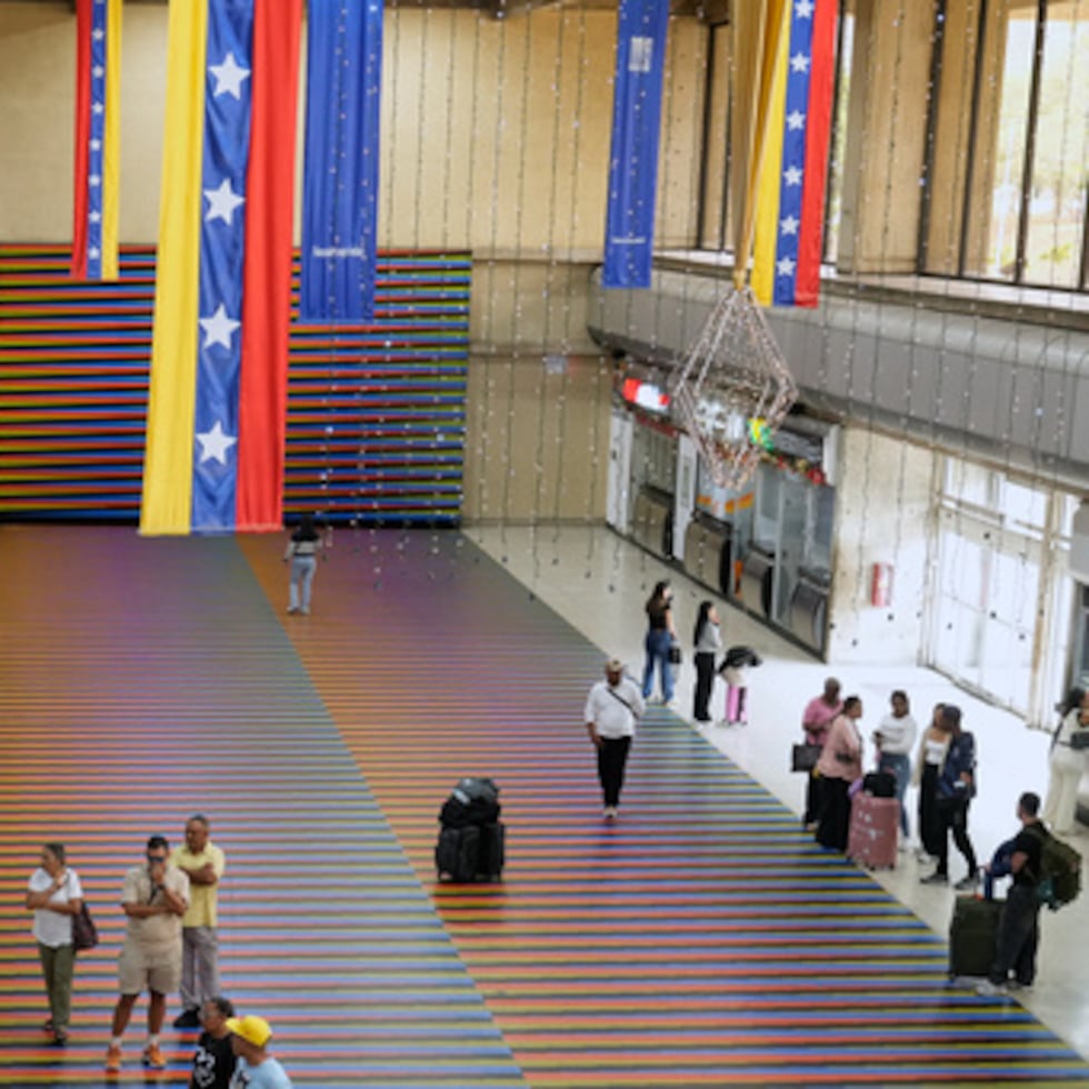 Viajeros esperan en la sala principal del Aeropuerto Internacional Simón Bolívar de Maiquetía, Venezuela, el domingo 13 de noviembre de 2025, después que varias aerolíneas internacionales cancelaran vuelos tras una advertencia de la Administración Federal de Aviación de Estados Unidos sobre una situación peligrosa en el espacio aéreo venezolano. (Foto AP/Ariana Cubillos)