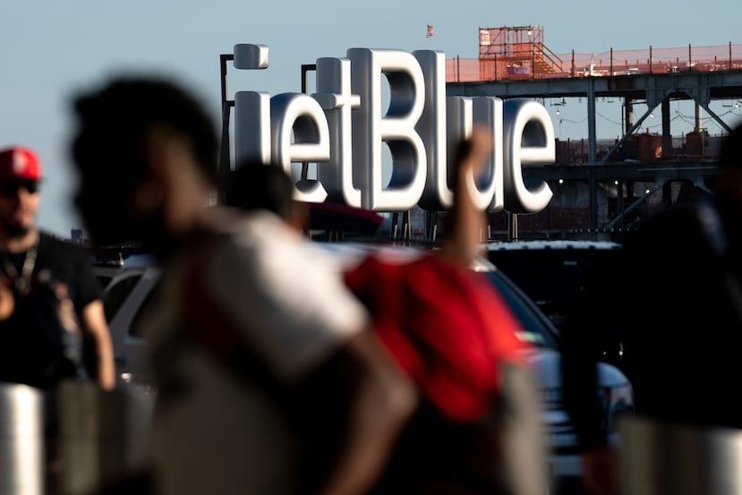 Viajeros pasan junto a un cartel de JetBlue antes del fin de semana feriado del 4 de julio en el aeropuerto John F. Kennedy.