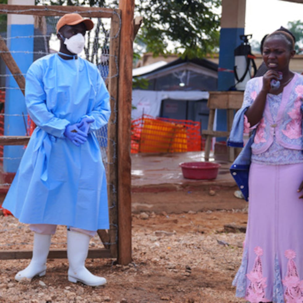 Los vecinos observan cómo el personal sanitario transporta el ataúd de una víctima del ébola en el Centro de Tratamiento del Ébola del Hospital General de Bunia, en Ituri (Congo).