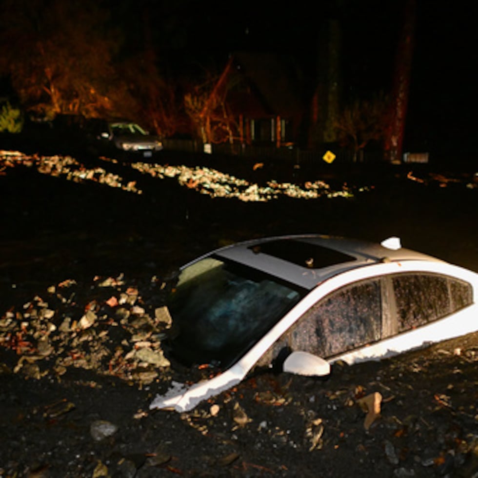 Un auto se ve enterrado en lodo tras una inundación.