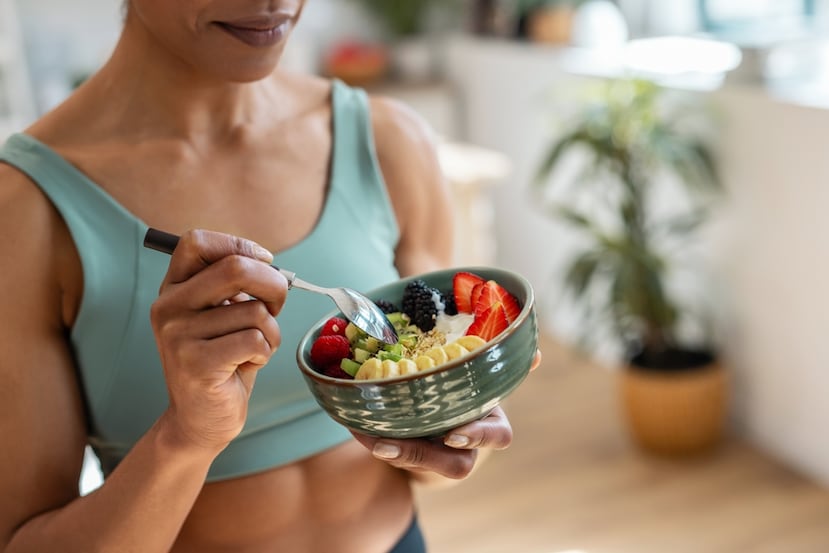 Close Up Of Athletic Woman Eating A Healthy Fruit,Bowl
