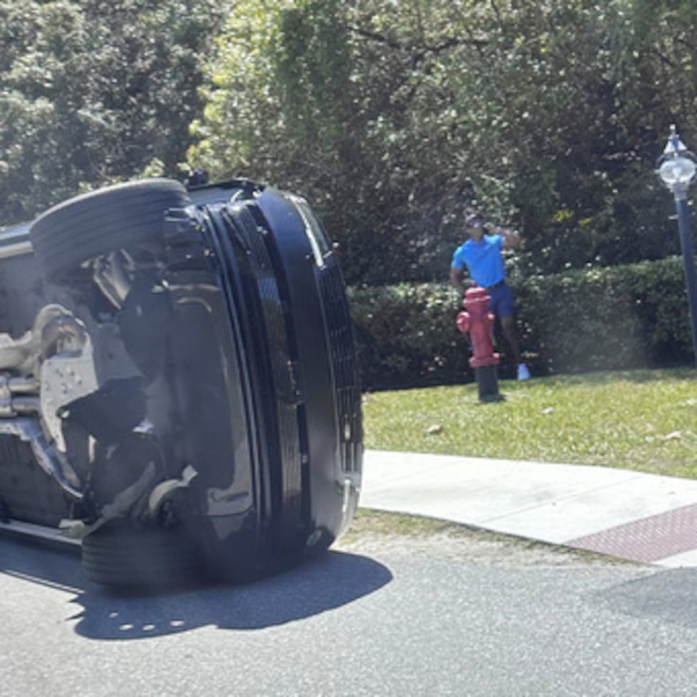 El golfista Tiger Woods junto a su vehículo volcado en Jupiter Island, Florida, el viernes 27 de marzo de 2026. (AP Photo/Jason Oteri)