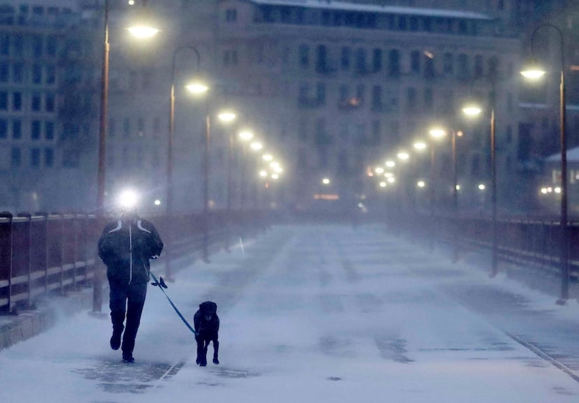 Un corredor y su perro soportan el frío extremo mientras cruzan el puente Stone Arch. (AP)